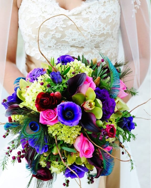 Purple and green wedding bouquet with peacock feathers