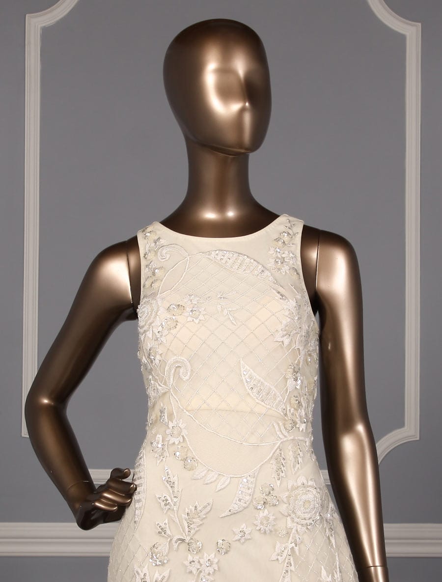 This incredible Carmen Marc Valvo Evelyn C90071 wedding dress is Brand New!  The workmanship on this gown is out of this world!  Intricate detail from top to bottom!  It is made from beaded and embroidered tulle with a soft stretch jersey lining.  The beading and embroidery create a floral and lattice design.  This Evelyn gown is sleeveless with a scoop neckline, a sheath silhouette, a high / sheer back and a chapel length train.