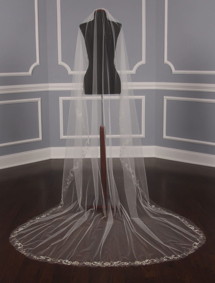 This beautiful Homa Bridal 800 BV bridal veil is Brand New and has its Homa Bridal hang tag attached!  The veil is made from diamond white tulle with a cut / raw edge.  Gorgeous silver embroidery and beadwork make this veil special and elegant.  There are scattered silver back crystals throughout the veil along with pearls, faceted crystals and aqua color beads near the embroidery.  This veil is one layer and chapel length.  A perfect compliment to your diamond white, or off white, wedding gown!