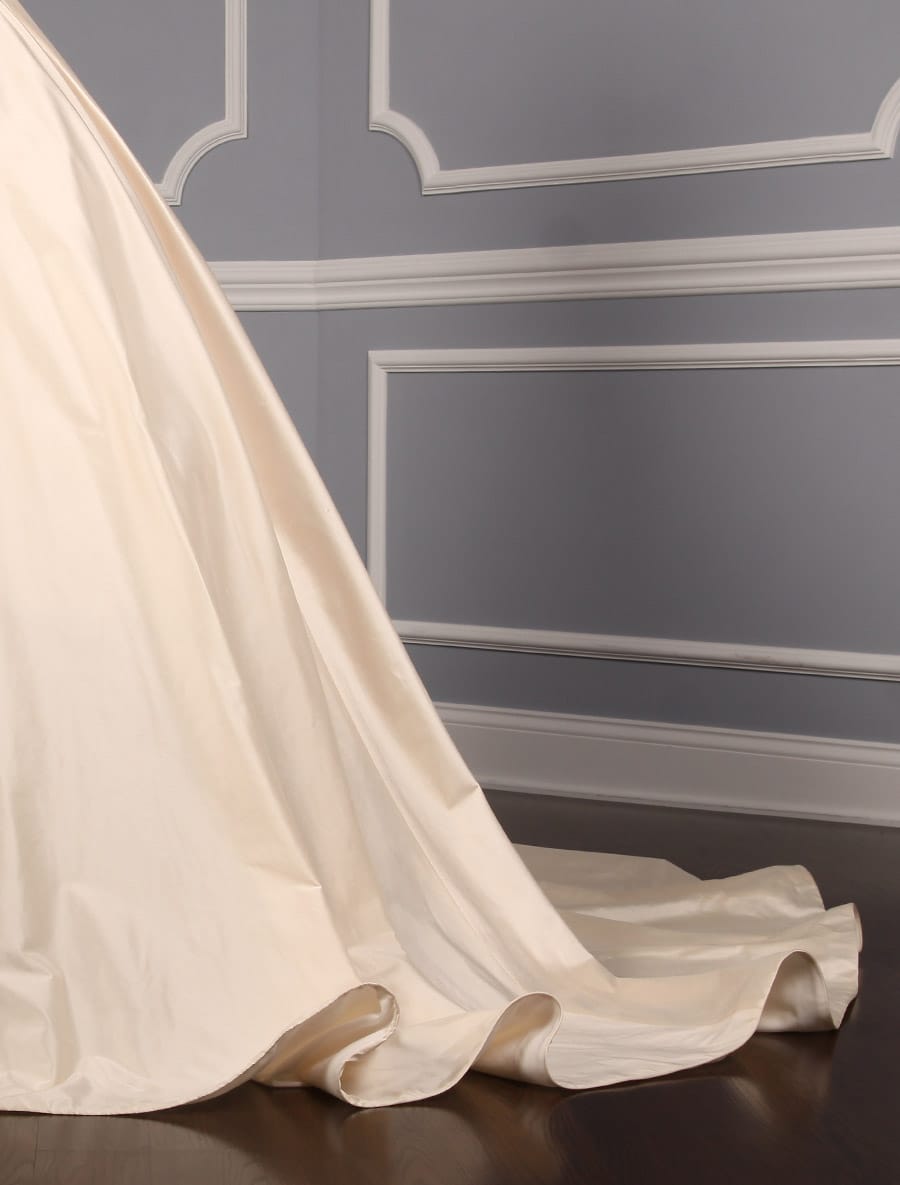 This Romona Keveza Legends L7130 wedding dress is Brand New!  It is made from beautiful silk shantung taffeta with lace appliques.  The ivory color is a vanilla shade, a bit of a warmer ivory.  This Romona Keveza Legends wedding dress is strapless with a ballgown silhouette, a high low hemline and a chapel train.  Side seam pockets are hidden in the skirt and are perfect for holding a few tissues or your lipstick.  You will definitely 'wow' your guests as you walk down the aisle in this stunning couture creation!